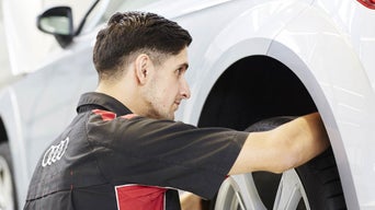 Service technician rotating a tire of an Audi vehicle.