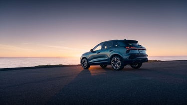Three-quarter rear-view of the Audi Q3 parked overlooking a body of water during dusk.