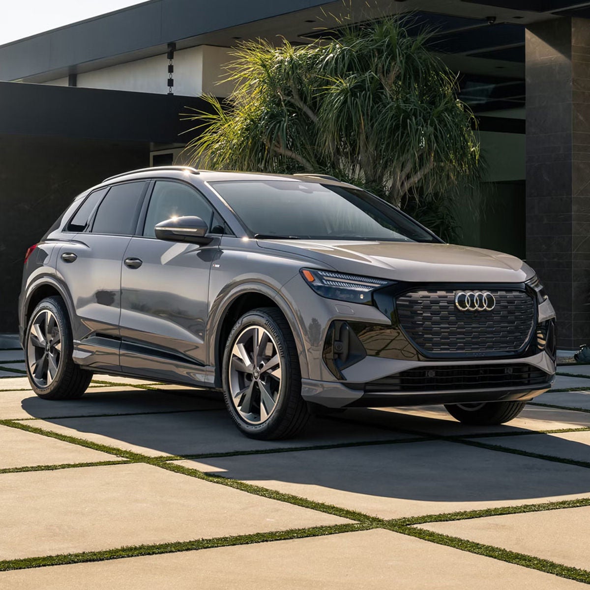 Three-quarter front view of the Audi Q4 e-tron parked in front of a modern home.