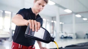 Service technician servicing vehicle with hood open.