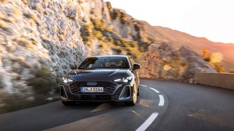 Front view of a 2025 Audi A5 model driving on a mountain road.
