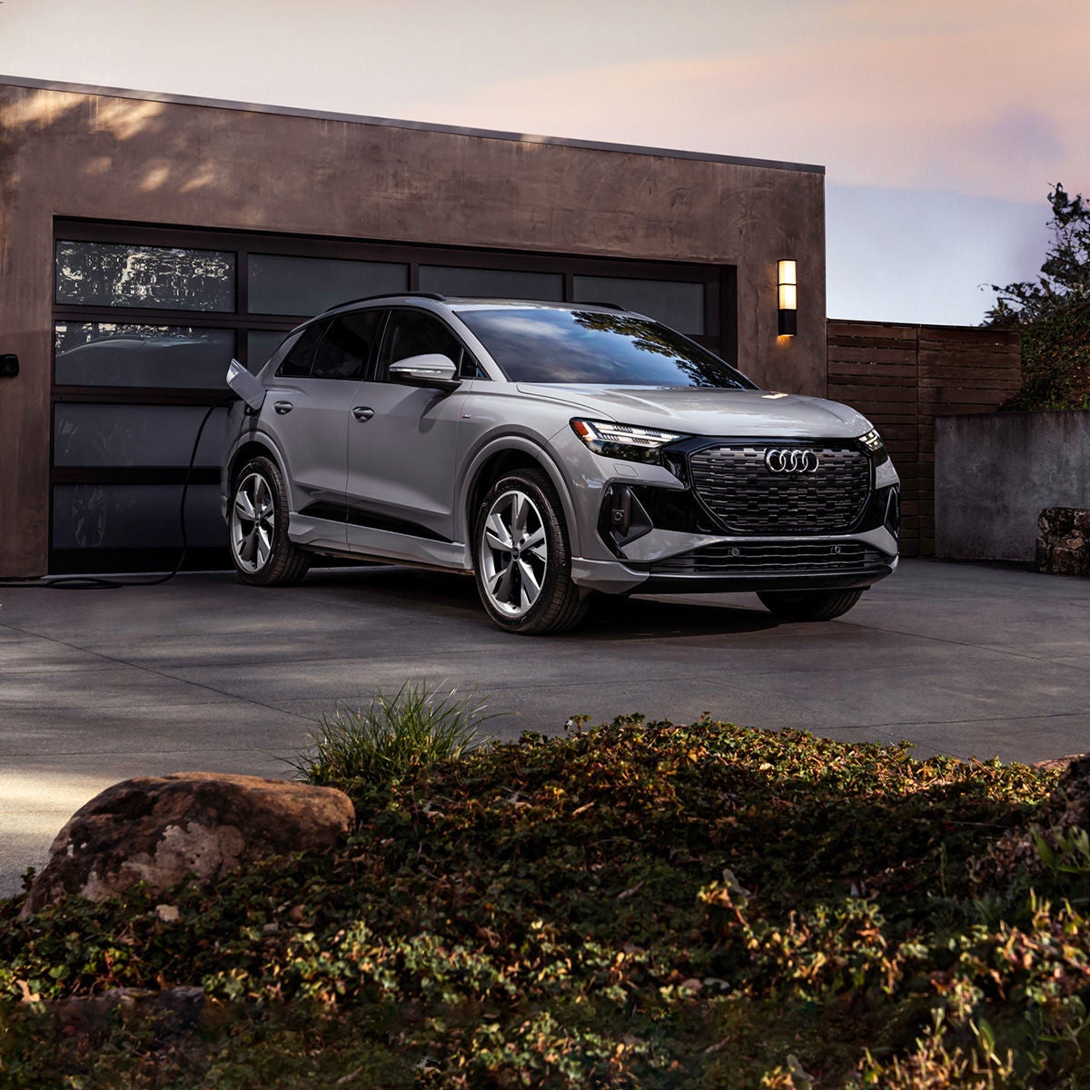 2024 Audi Q4 e-tron plugged up charging in front of a modern house