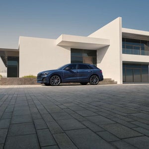 2026 Audi Q8 in blue at modern architecture — discover the Q8 at Audi Sewickley near Pittsburgh