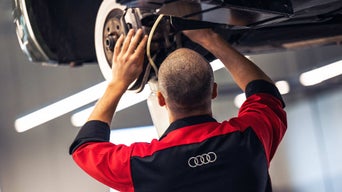 Audi Technician inspecting tires of vehicle 