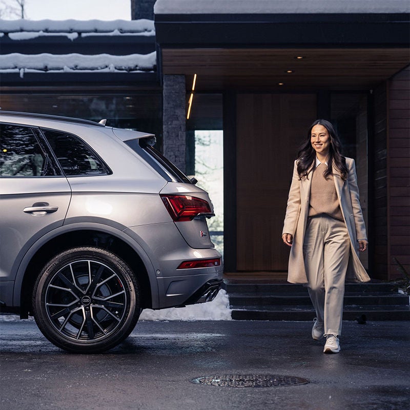 Image of a woman walking confidently behind an Audi