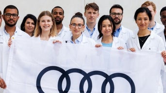 Group of Newcomers holding Audi flag
