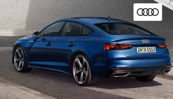 2025 Audi A5 Sportback parked in front of downtown Dayton skyline at sunset. 