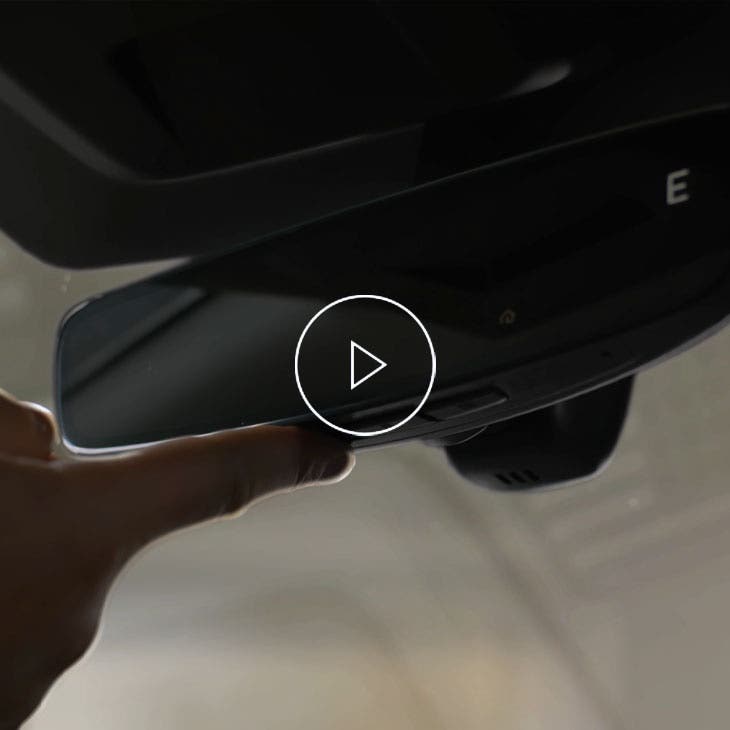 A person pressing the homelink button on their rearview mirror.