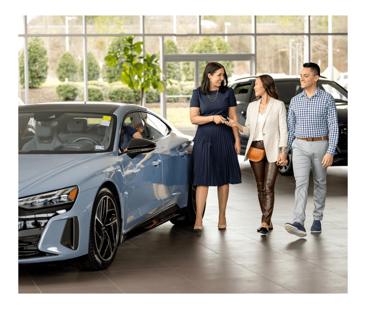 Couple with salesperson beside 2022 Audi RS e-tron GT in Suzuka Gray in a bright showroom