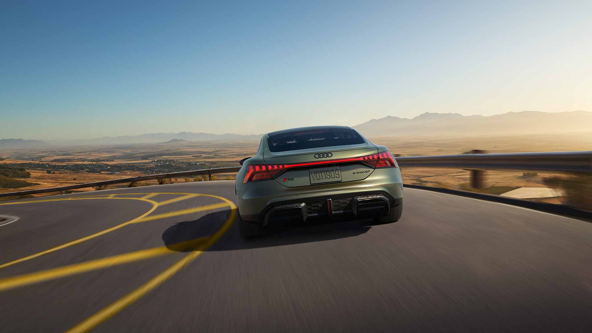 A man charging an Audi e-tron GT in front of a home. 