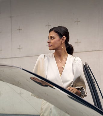 A person standing near an open door of an Audi vehicle.