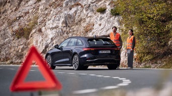 An Audi mechanic working on a car on the side of the road. 