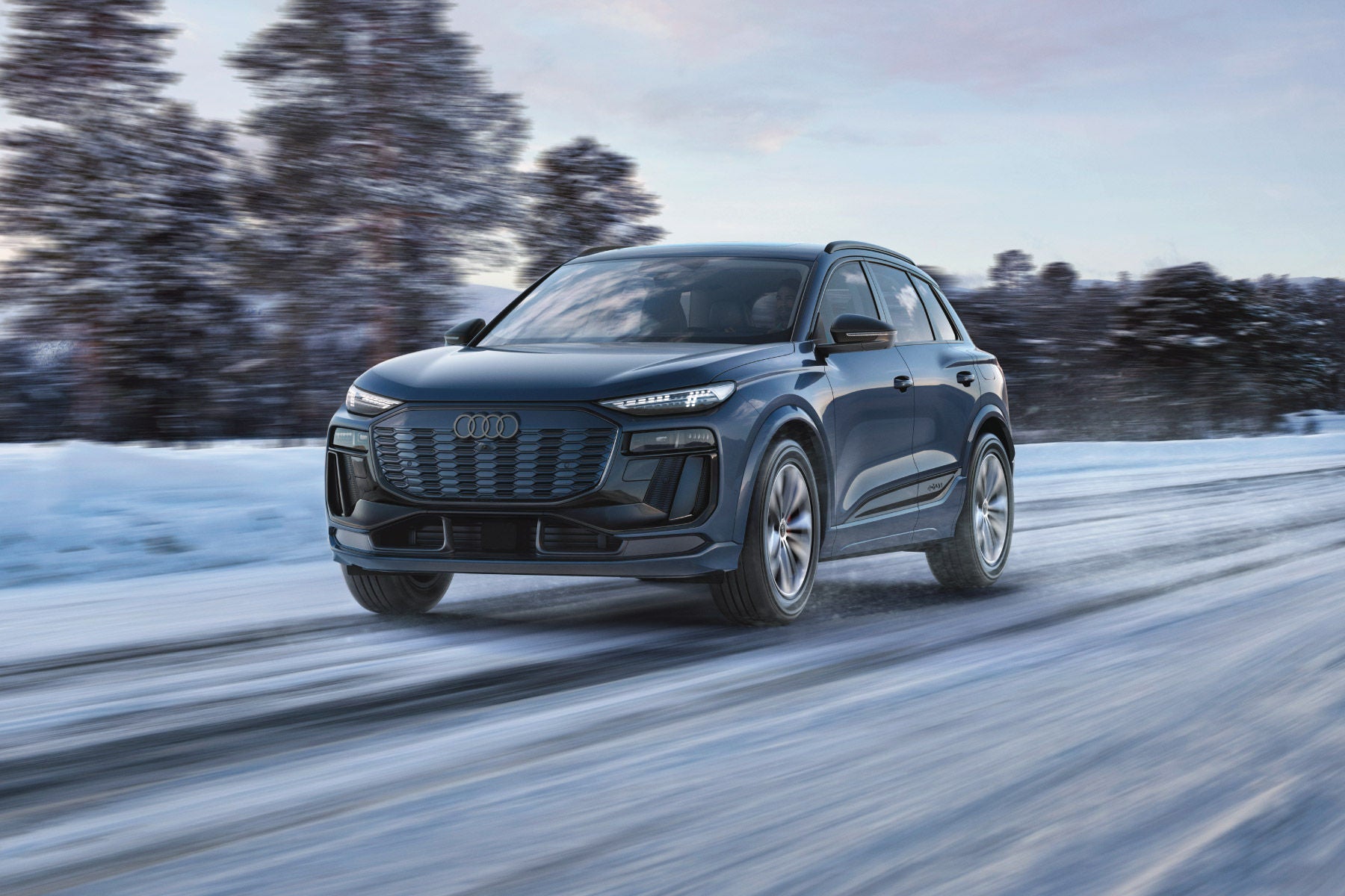 Audi Q6 e-tron driving confidently through snowy roads, demonstrating superior grip and control with Audi winter tires installed