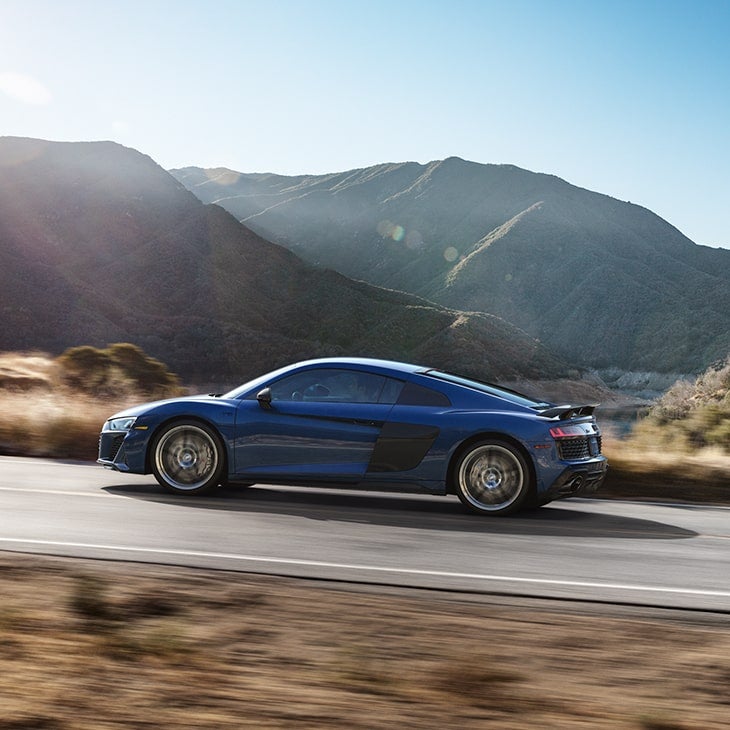 Side profile of the Audi R8 Coupe driving on the road.
