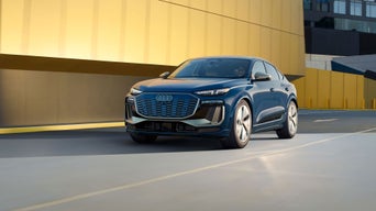 Three-quarter front view of the Audi SQ6 Sportback e-tron accelerating on a city road.
