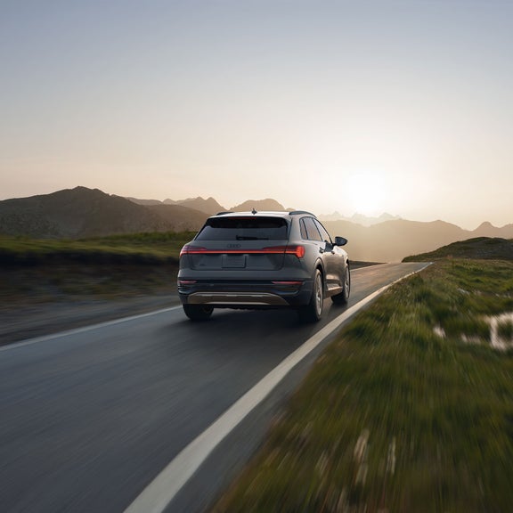 Rear profile of a gray Audi Q8 e-tron accelerating. 