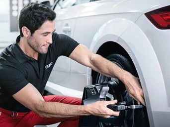 Service technician servicing vehicle with hood open.