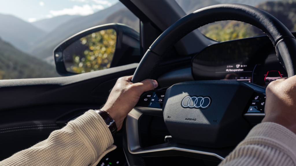 Person holding the wheel of an Audi vehicle.