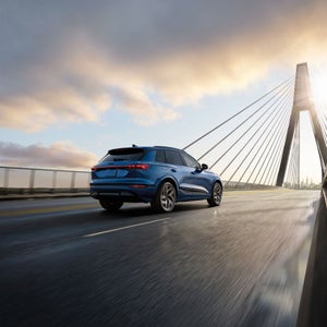 Three-quarter rear view of the Audi SQ6 e-tron accelerating on a large bridge.