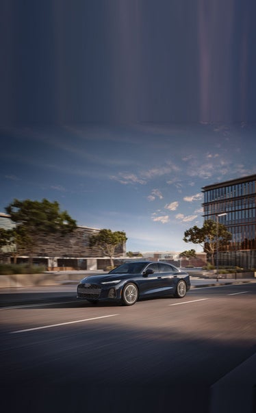 2026 Audi A6 driving past modern architecture
