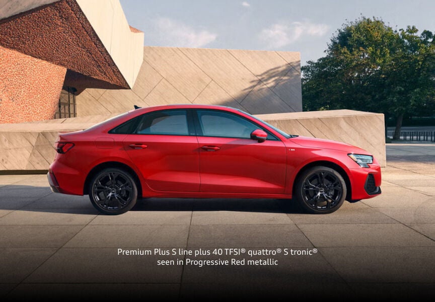2026 Audi A3 Premium Plus S line quattro in Progressive Red metallic, side profile by modern architecture.