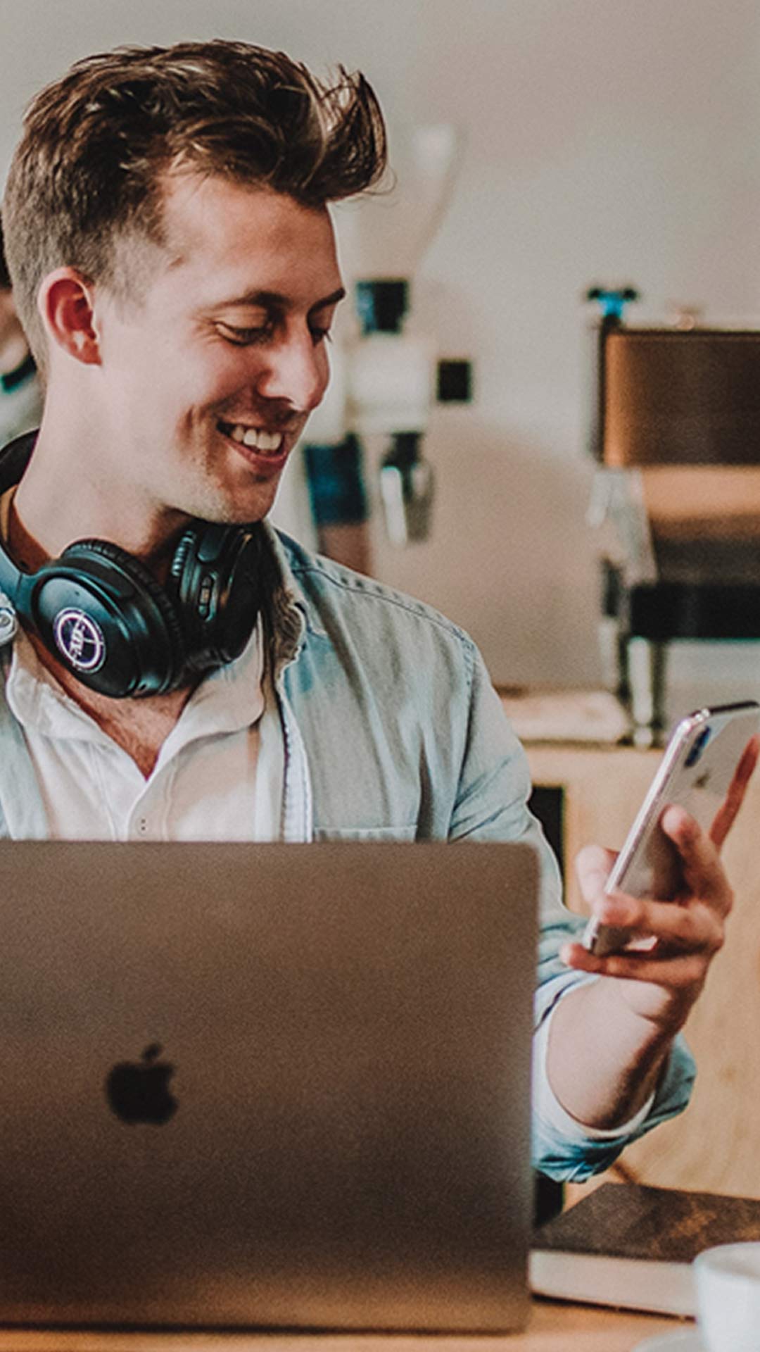 Man smiling at phone while working on laptop