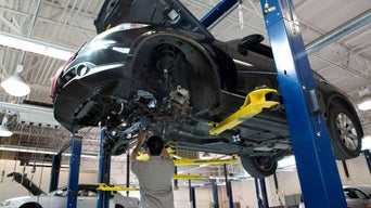 Service technician servicing an Audi vehicle on a vehicle lift.