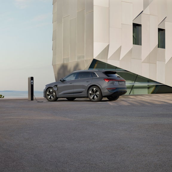 Side profile of a gray Audi Q8 e-tron parked and charging. 