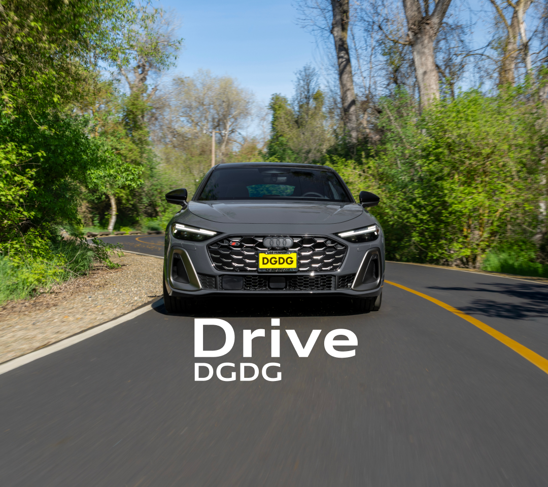 Front view of a grey Audi S5 sport sedan driving on a winding, tree-lined road.