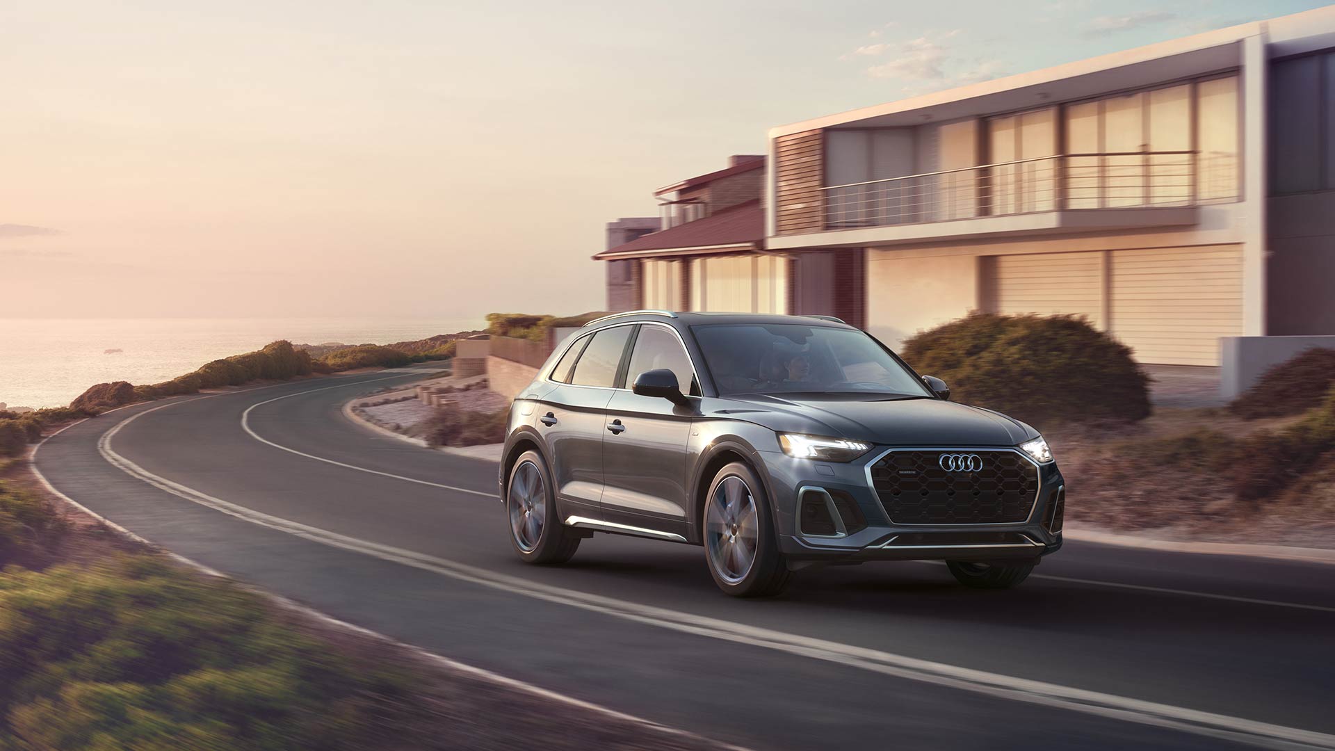 Audi Q5 accelerating down coastal road during sunset