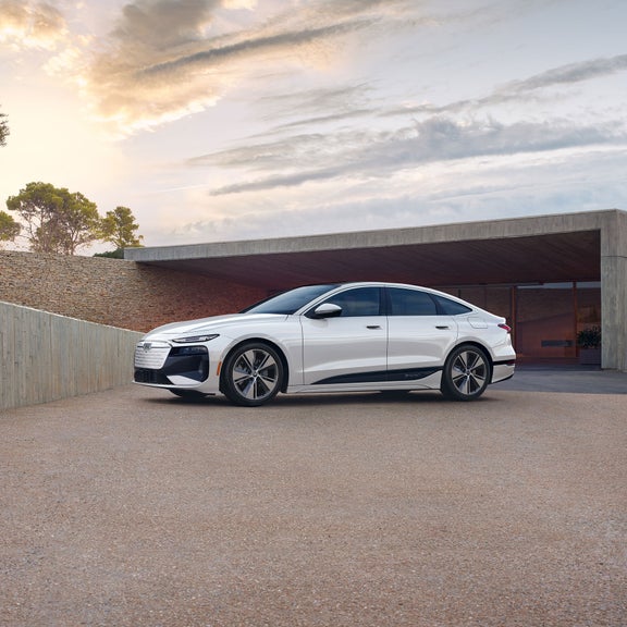Vue latérale de trois quarts de l'Audi A6 e-tron garée près d'un bâtiment moderne.