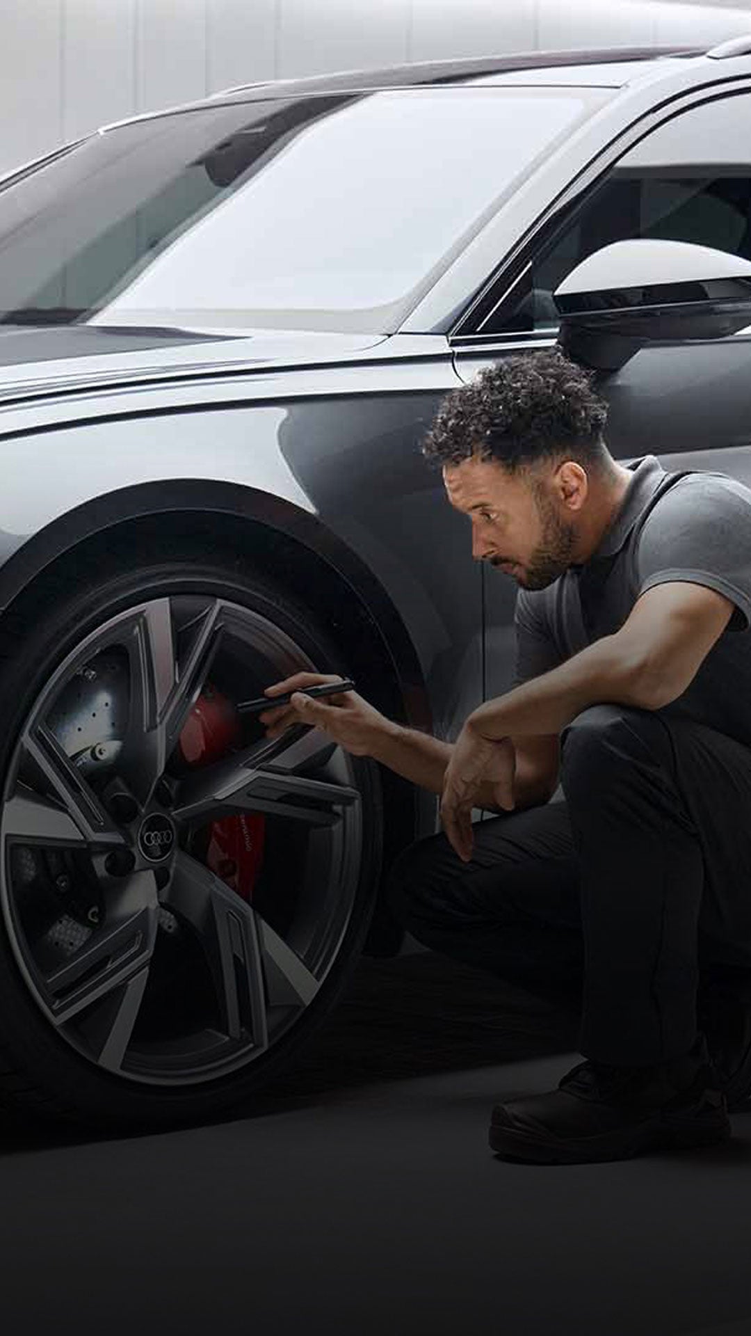 An Audi technician inspecting the wheel of an Audi vehicle. 