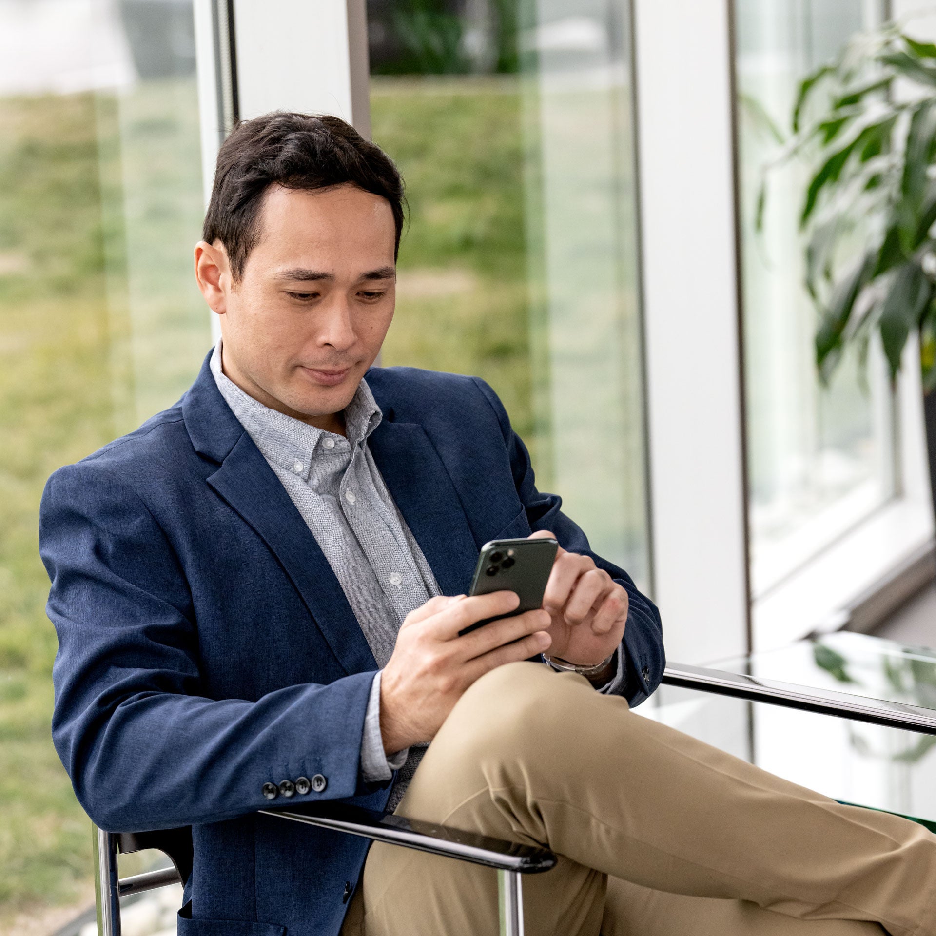 A man sitting on a chair looking at his phone.