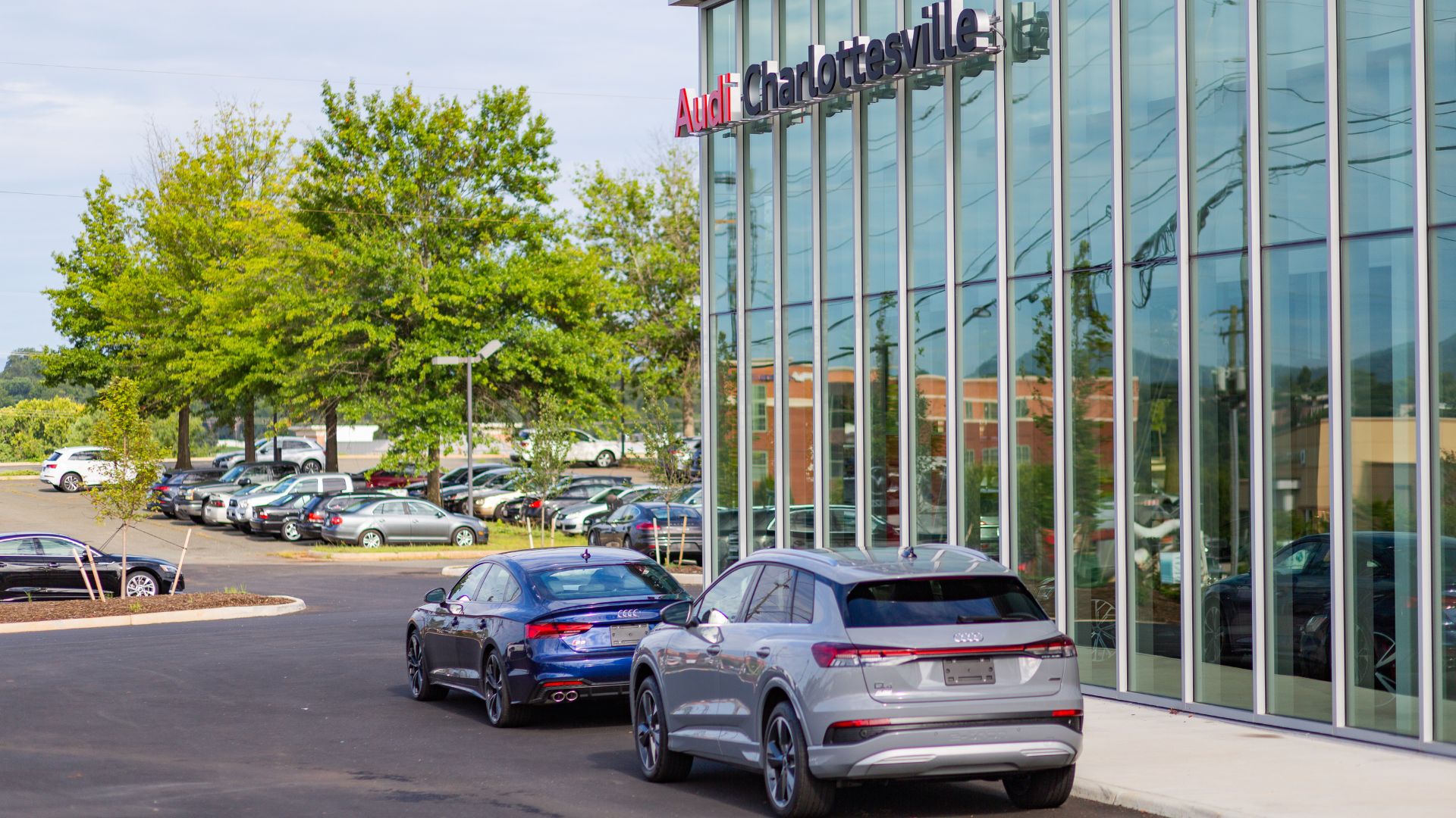 The Audi Charlottesville dealership building with two cars parked in front