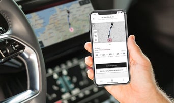 Gros plan sur le smartphone d'une personne montrant la fonction de planification de trajet myAudi.