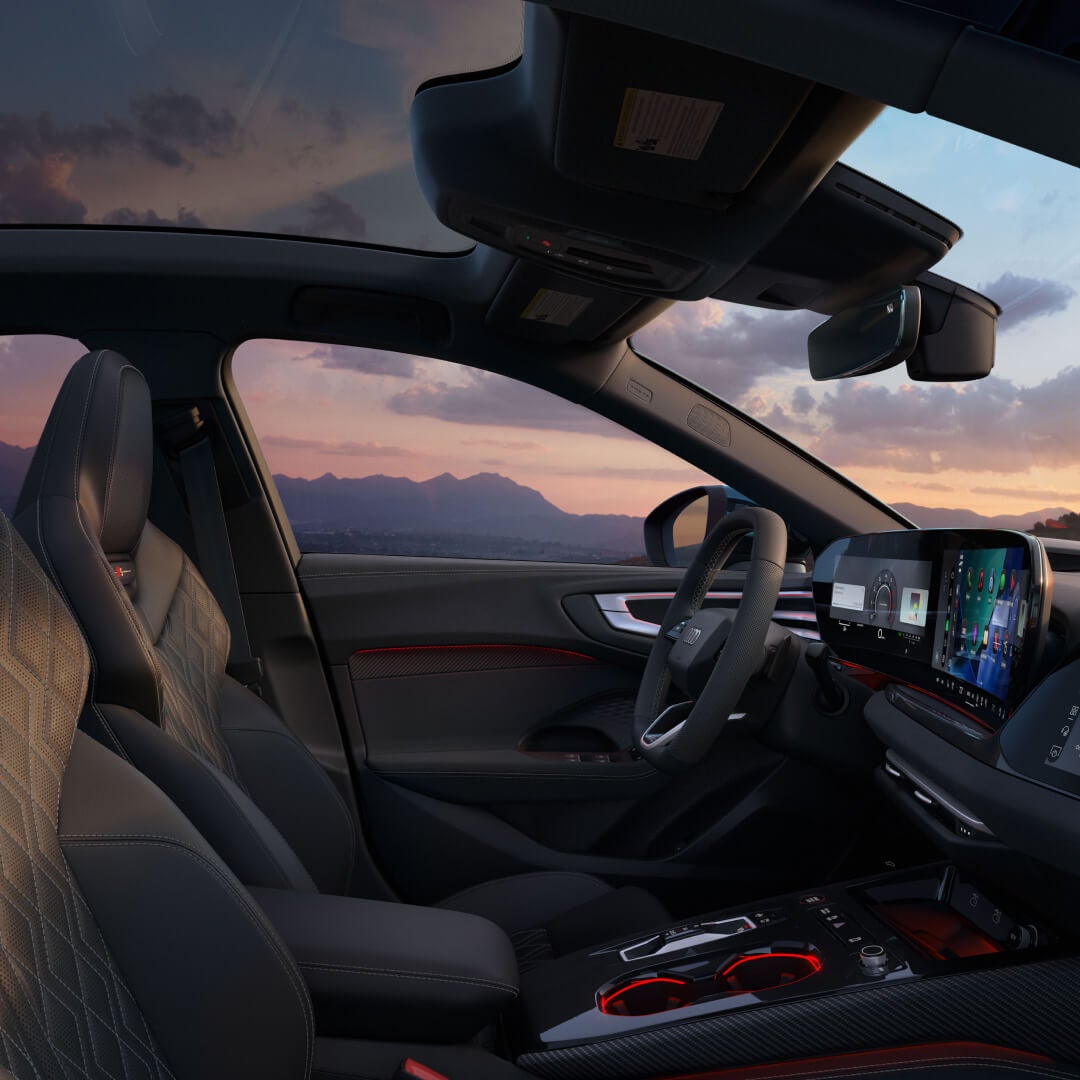 Interior view of a blue 2026 Audi S5 with a mountain sunset background seen through the windows.