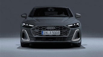 Front view of a 2025 Audi A5 model with headlights on.