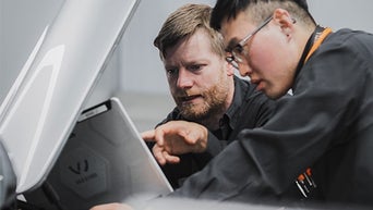 Two Audi technicians looking at a clipboard. 