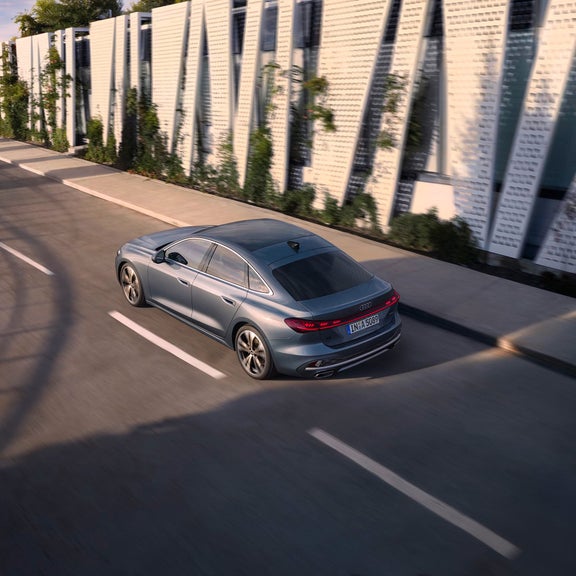 Aerial rear view of the Audi A5 accelerating on a city road.