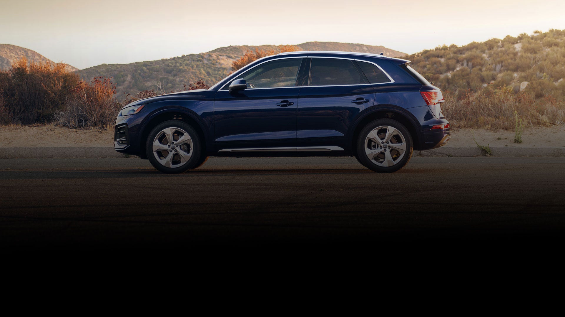 Side-view of an Audi Q5 parked on a desert road.