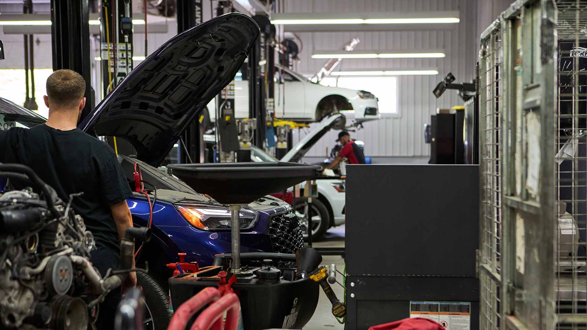 Deux techniciens de service entretenant des véhicules Audi.