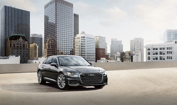 Audi A6 parked on rooftop with city view