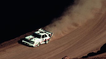 Aerial front-view of an Audi rally vehicle accelerating on a dirty path.