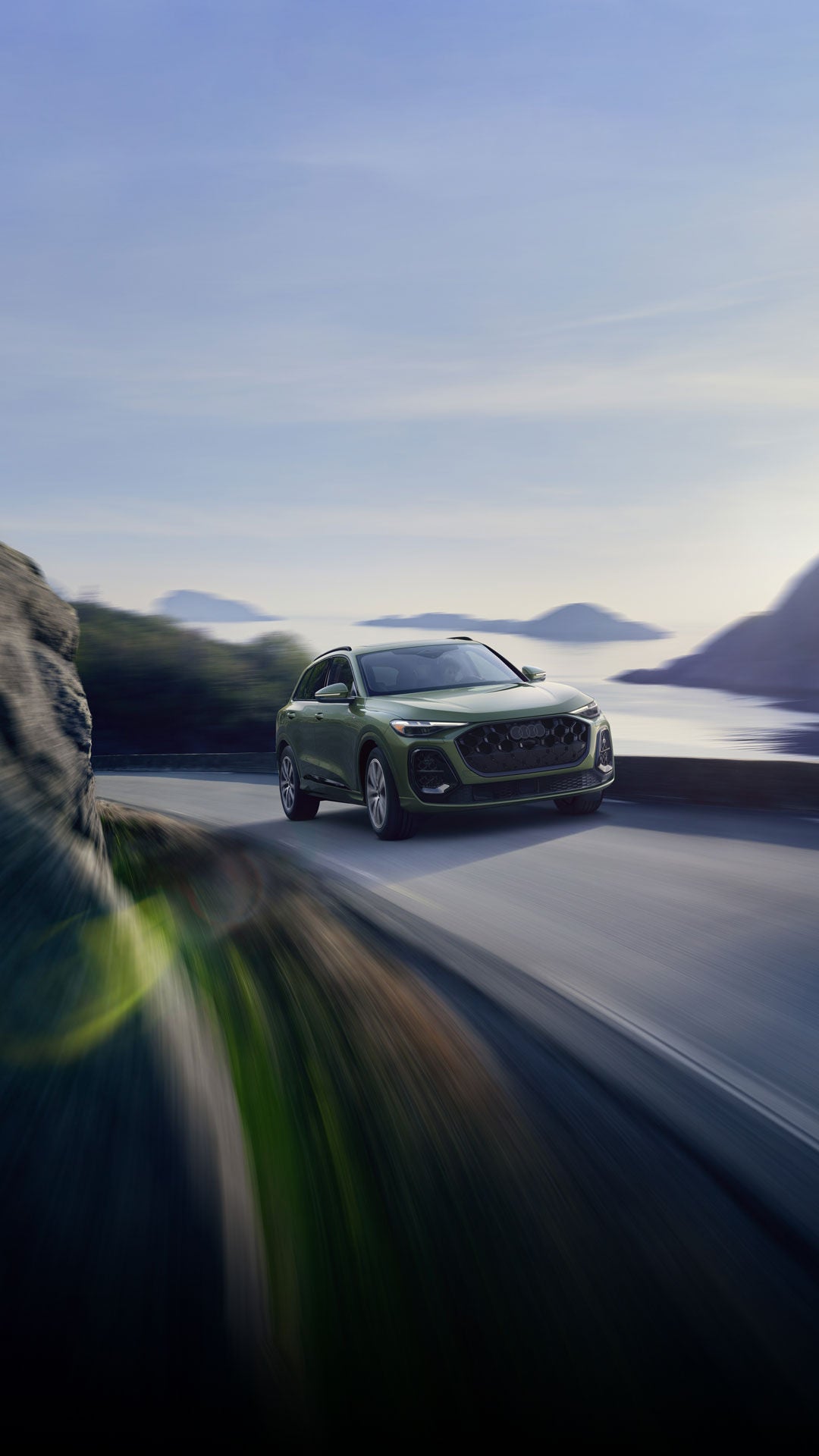 Three-quarter front-view of the Audi Q5 accelerating on a hillside road.