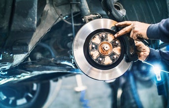 Service technician servicing vehicle axle. 