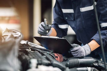 Mechanic holding a clipboard in an engine bay