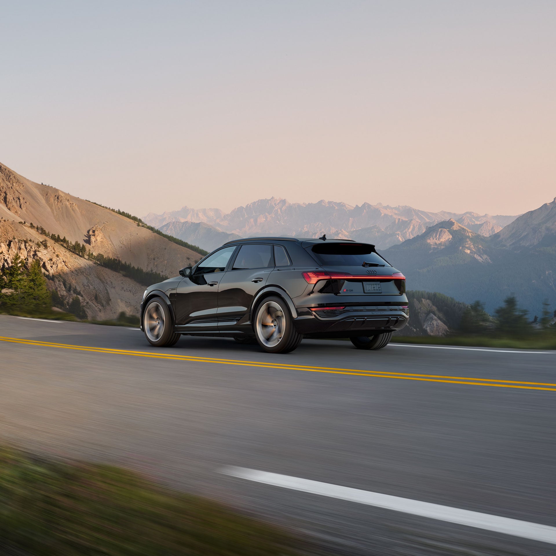 Side-view of the Audi SQ8 e-tron accelerating on a mountain road.