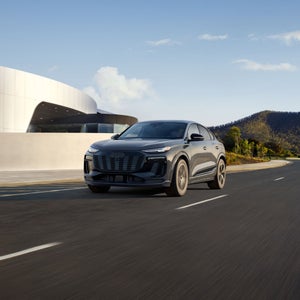 Three-quarter front view of the Audi Q6 Sportback e-tron accelerating. 