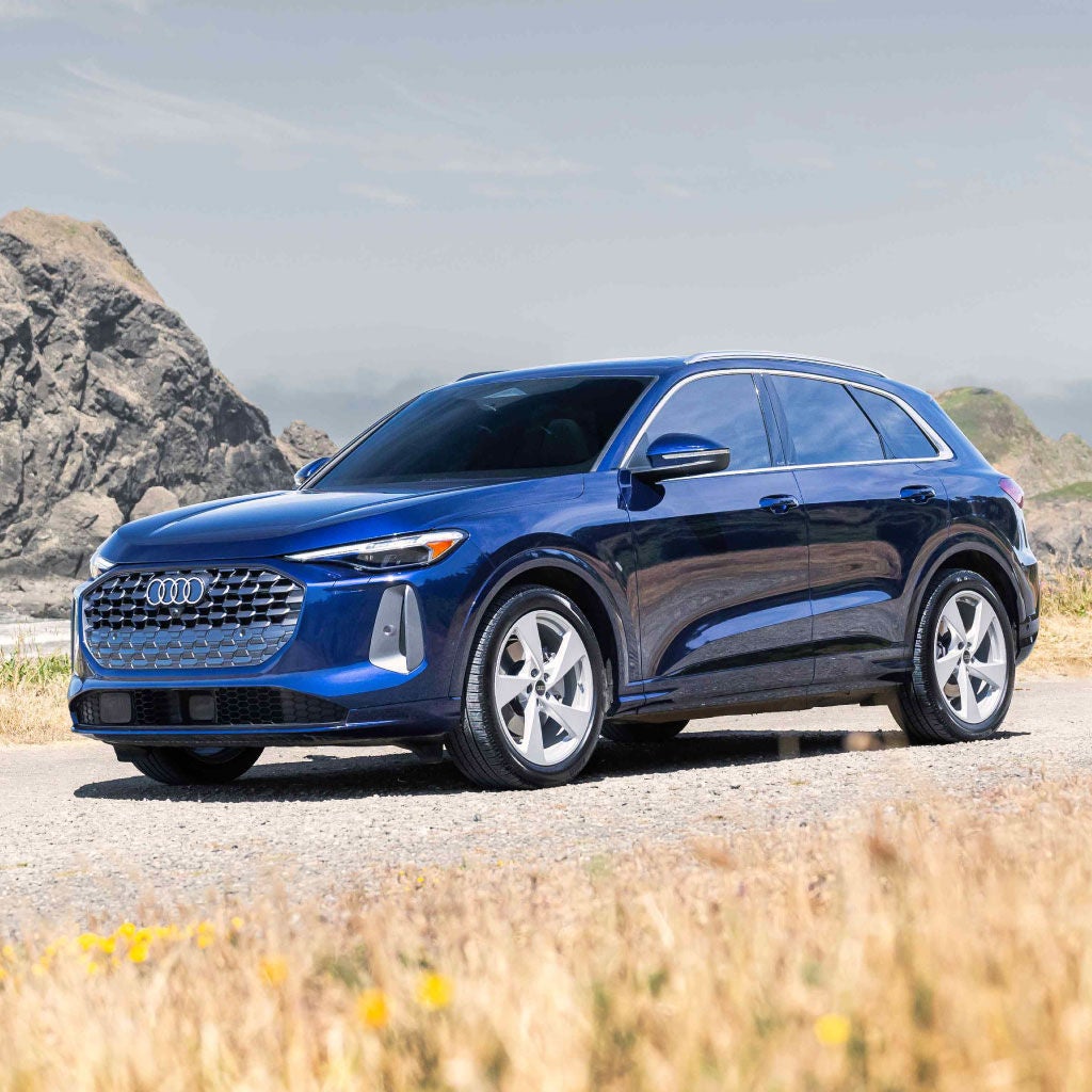 A blue Q5 parked with rocks behind it.