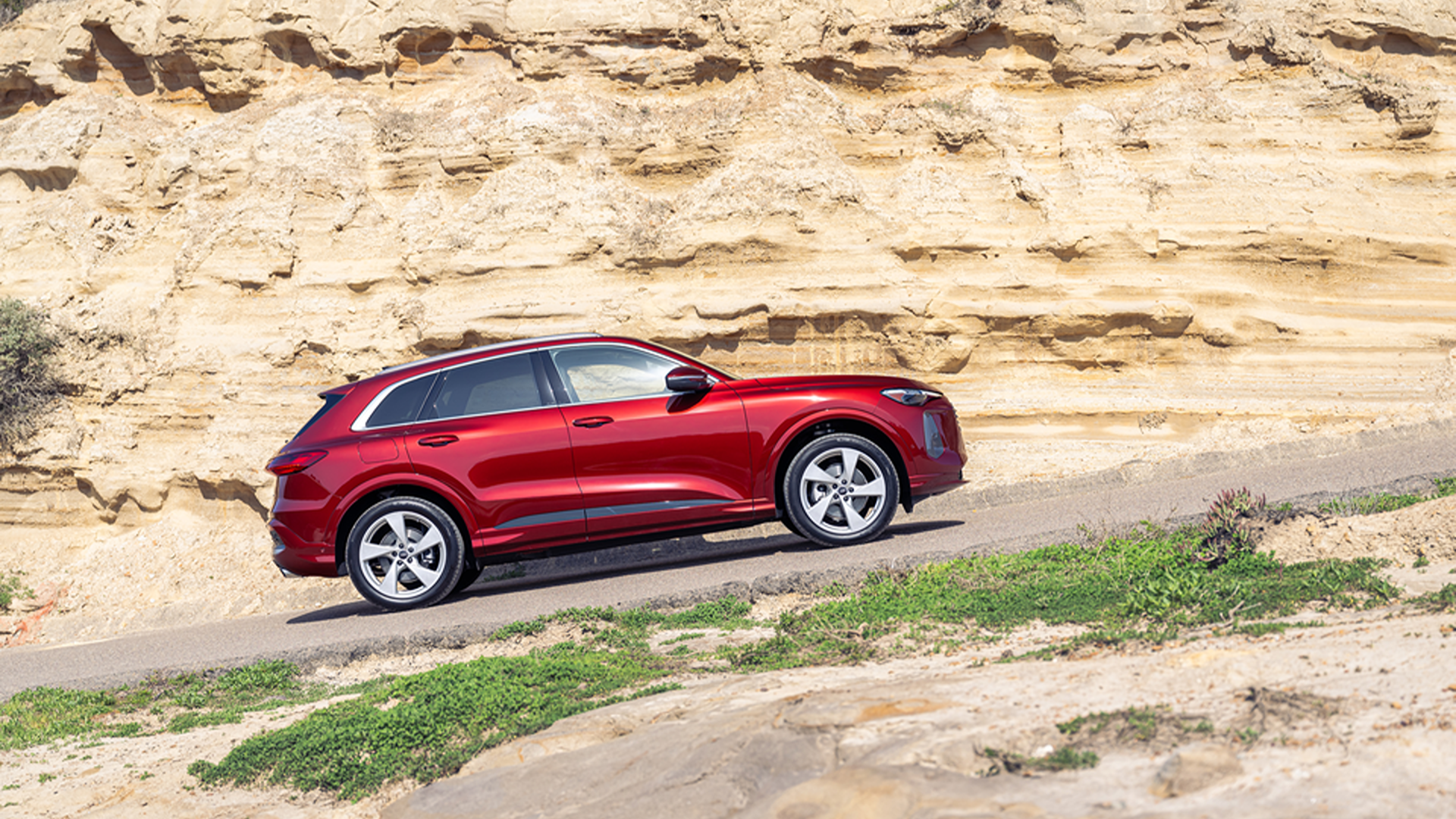 Red Q5 climbing a hill near a rock face